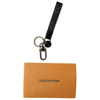 Louis Vuitton keychain with a black strap on an orange card with 'Louis Vuitton' branding.