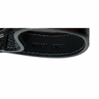 Close-up of a black leather product with visible branding on a white background