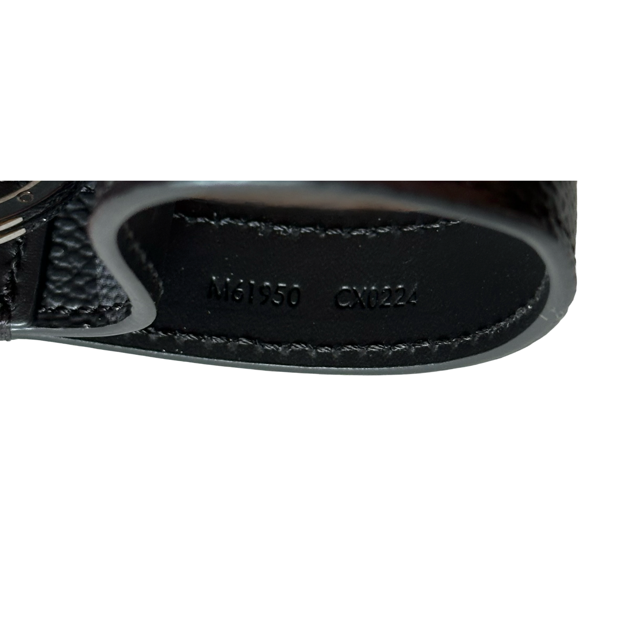 Close-up of a black leather product with visible branding on a white background